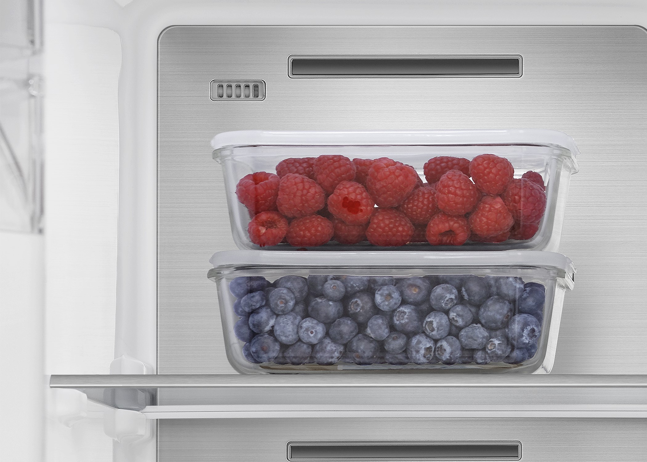 An image showing blueberries and raspberries in containers in the frozen section of the RS818 fridge.